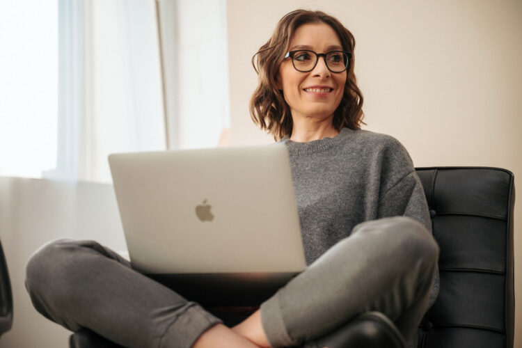 Cecilia Barriga mit Laptop auf dem Schoß im schwarzen Sessel