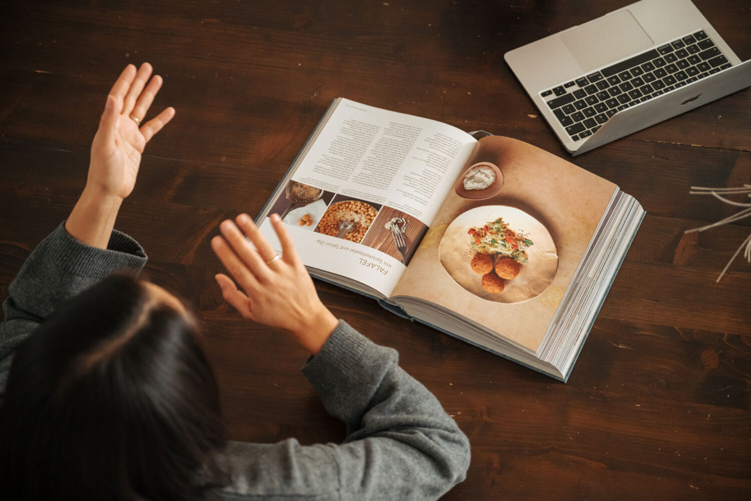 Rezeptbuch der Ernährungsberaterin liegt auf Tisch mit Laptop